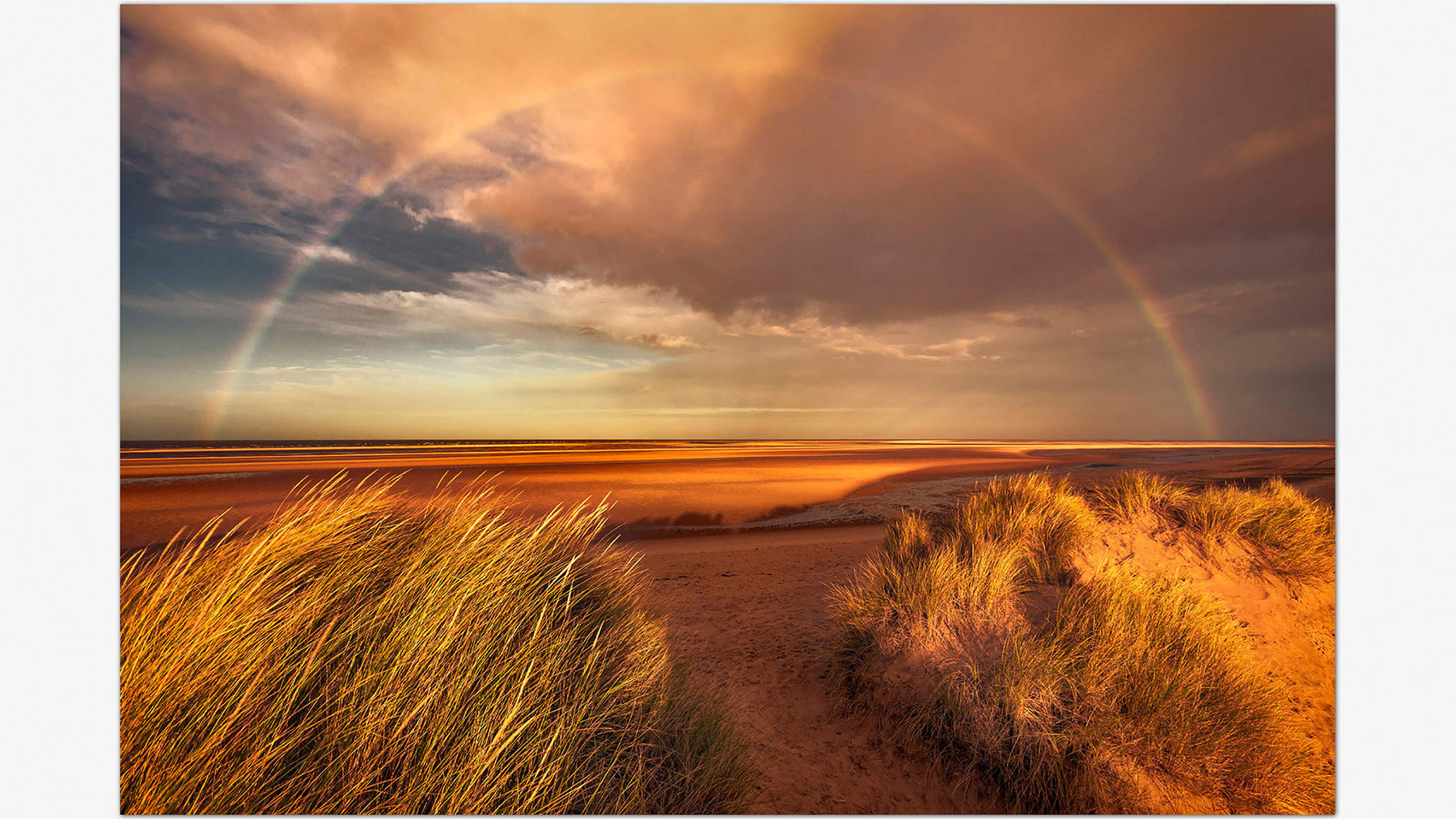 A rainbow over the beach during low tide at Holkham, Norfolk